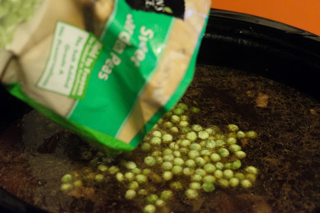 Frozen peas being added to the crock pot. 