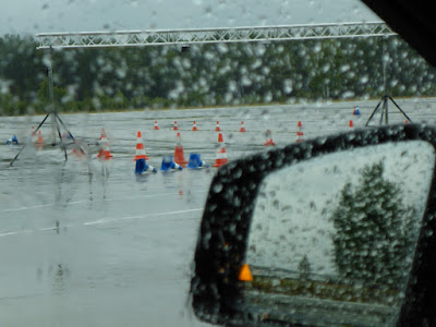 Blick durch eine regennasse Autoscheibe auf einen Fahrübungsparcours