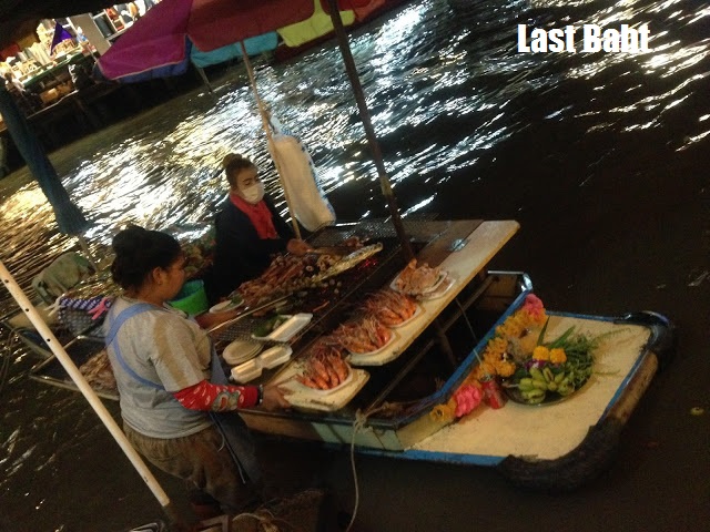 floating-market-vendors grileld fish served from a boat at Ampawah floating market, Thailand