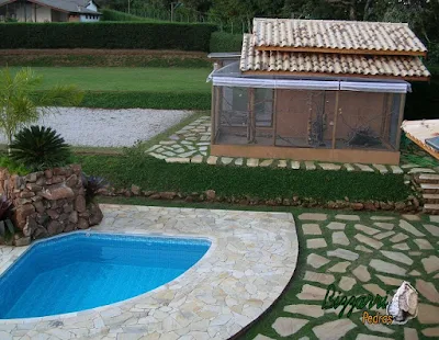 Pisadeira de pedra com pedra cacão de São Tomé em volta da construção da piscina e em volta da construção do viveiro de pássaros com as muretas de pedra, escada de pedra e o talude com grama amendoim em construção de casa em Atibaia-SP.