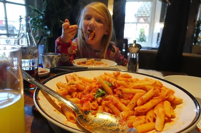 A large bowl of arrabbiata pasta in Prezzo with a young girl eating the pasta in the background