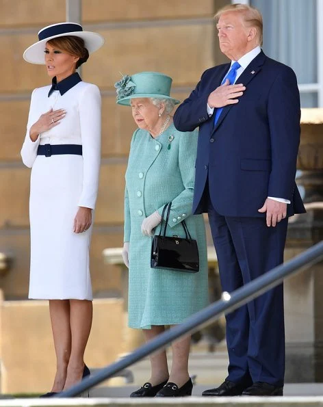 Melania Trump is wearing a custom white crepe dress with navy details by Italian fashion house, Dolce & Gabbana. Queen Elizabeth