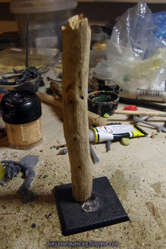 Photo showing a wooden stick taken from the backyard, cleaned of bark and glued vertically to a square, plastic base.