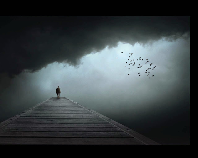 Imagen de un hombre solitario caminando a lo lejos mientras una bandada de aves vuelan en un cielo oscuro y lleno de grises nubes.