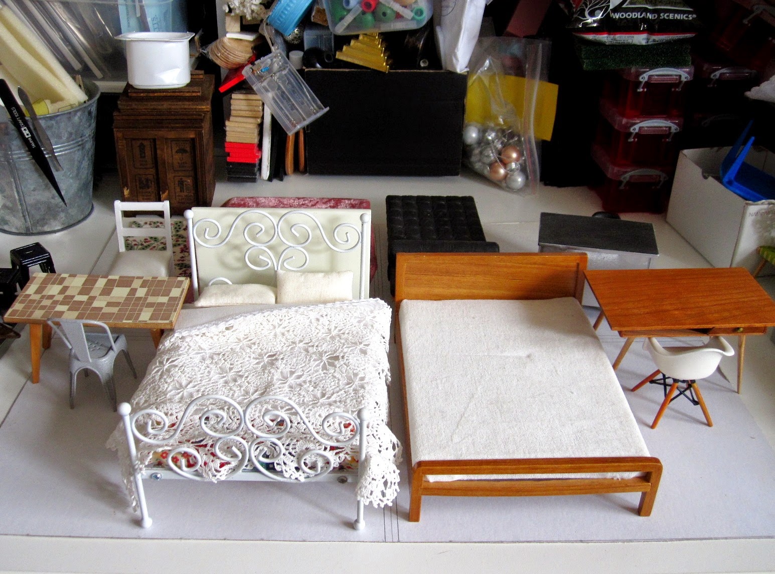 Four sets of modern dolls' house miniature furniture in different styles arranged in room settings on a piece of cardboard.