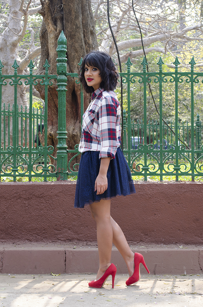 Image of style blogger wearing a plaid checked shirt, tutu skirt, red high heels with a mini bag, red lips and a wavy bob hairstyle