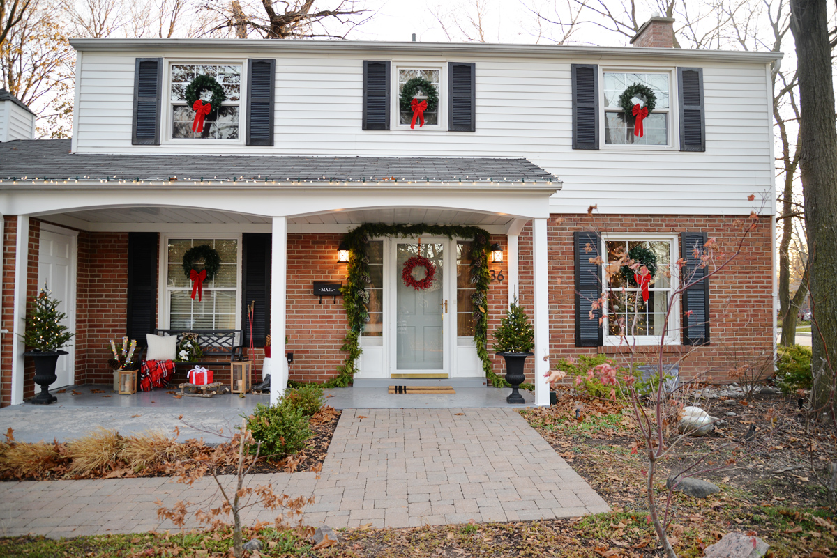 classic christmas decorations, colonial house with wreaths on windows, wreaths on exterior windows, wreath on chimney, large exterior wreath