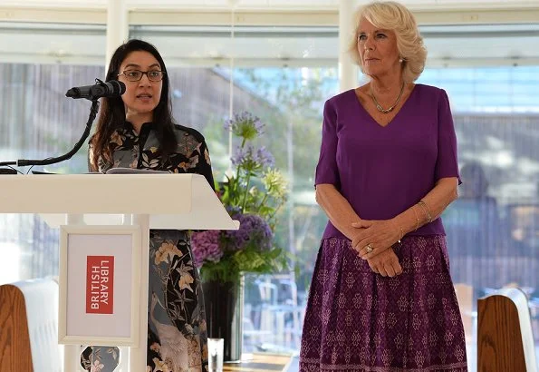 Camilla, the Duchess of Cornwall attended a literacy event for The Royal Society of Literature at the British Library. purple top and print skirt