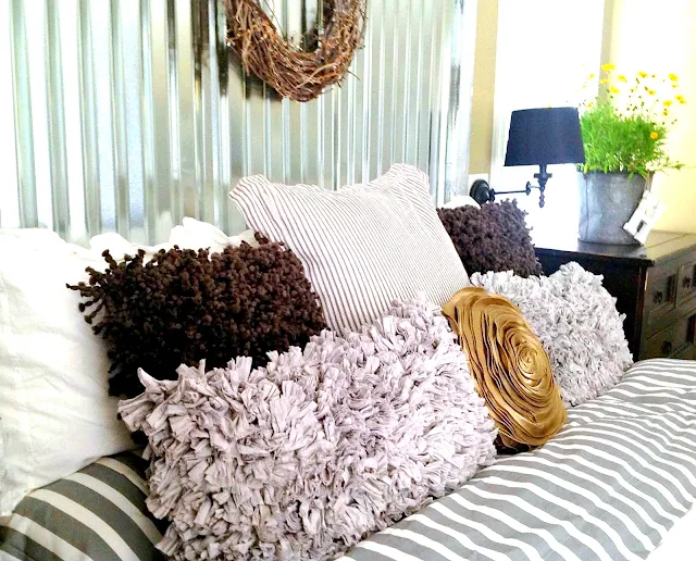 Gorgeous layered pillows, part of a fantabulous industrial metal siding headboard by Down To Earth Style, featured on I Love that Junk