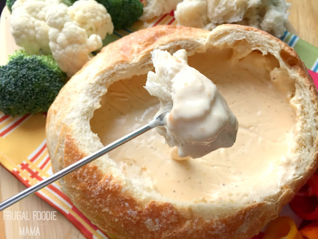 A soft and crusty bread bowl is stuffed with a beer & garlic infused fondue cheese and then heated until melted and gooey over a grill or campfire in this Grilled Beer Cheese Fondue.