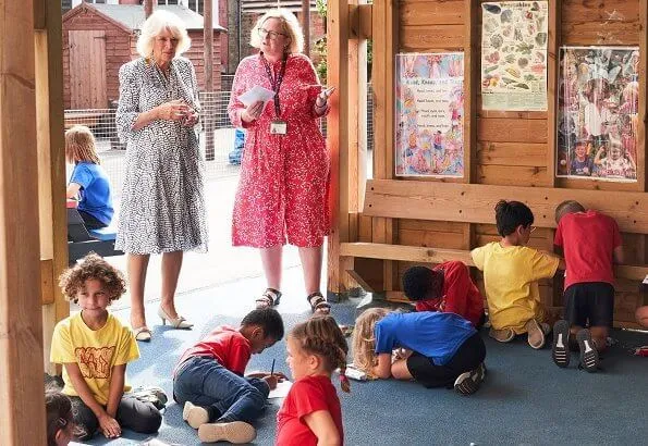 The Duchess of Cornwall is patron of The National Literacy Trust. The duchess wore a printed silk summer midi dress. beige pumps and bag