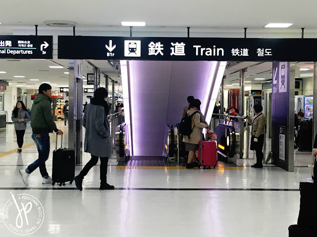 train signboard, escalator, people with luggage at the airport