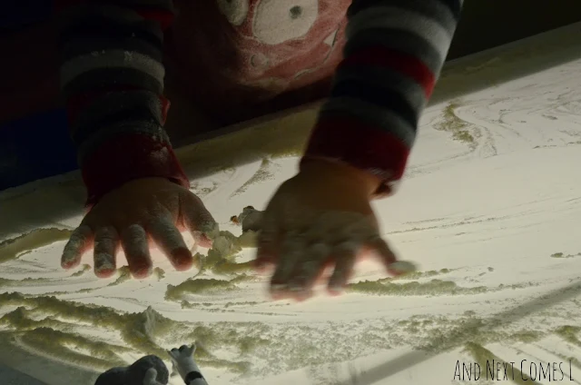 Closeup of toddler hands playing in flour on the light table