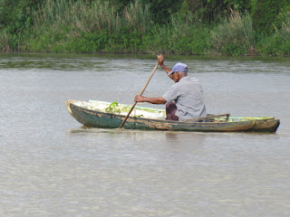 old man paddling a dugout canoe in Belize