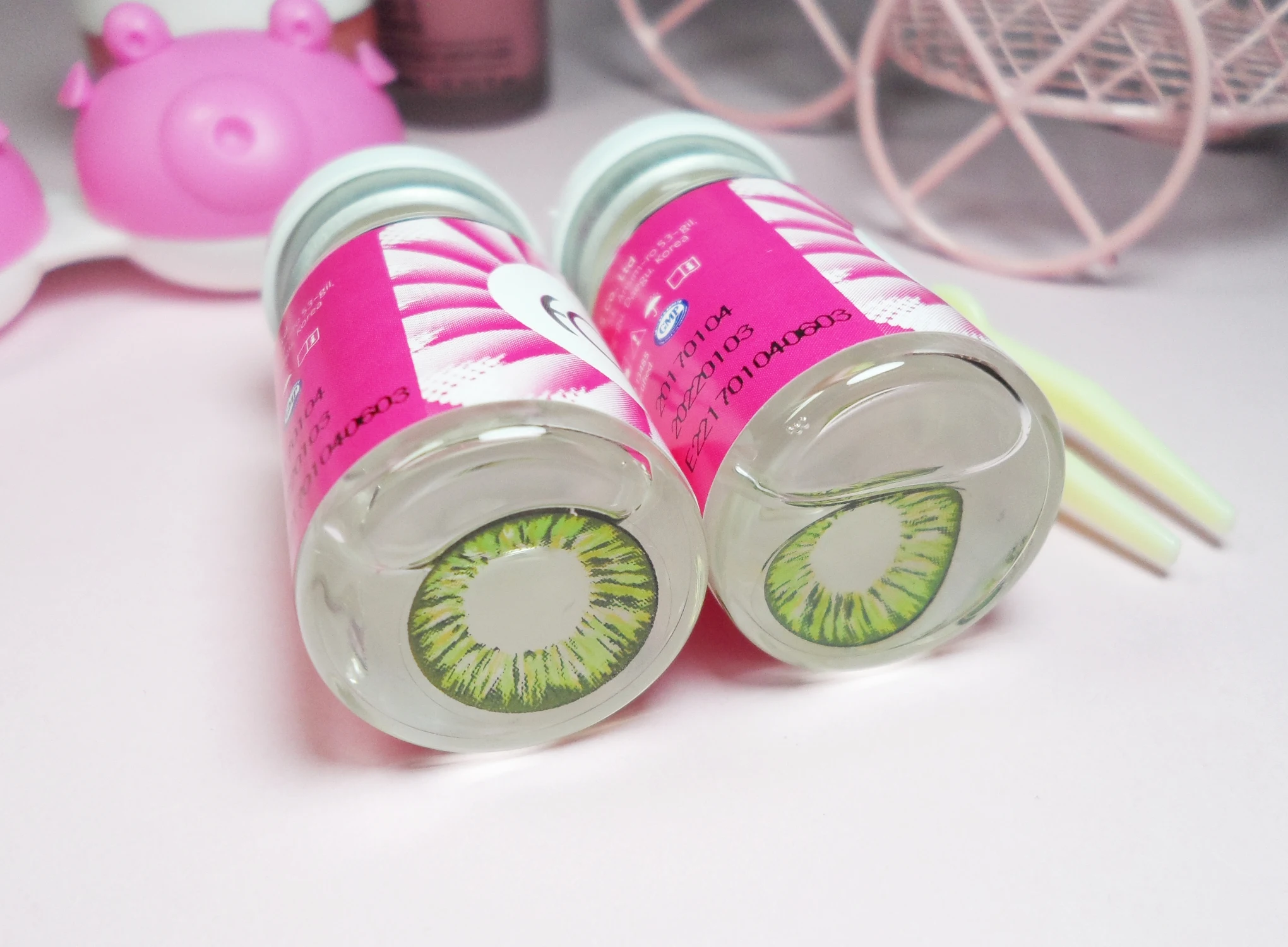 close-up of a green circle lenses in solution on a rosy studio's background