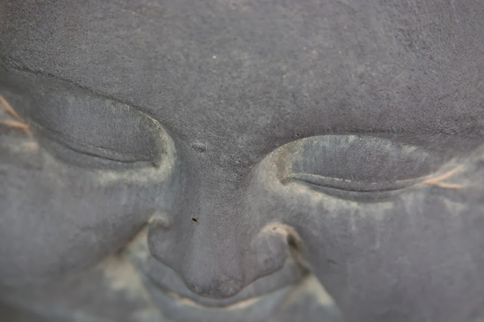 smiling face of a fat grey buddha