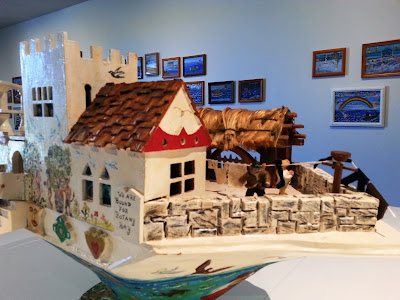 Miniature wooden painted artist's arks on display in a gallery.