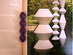Picture in a book of La Gardo Tackett's garden sculptures, with four purple wooden beads lined up next to it.