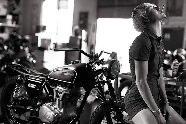 Girl smoking in a motorcycle workshop with an anguished look