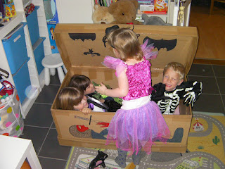 4 children trying to get into the same halloween coffin