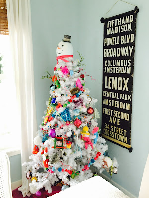 bright colored ornaments on  White Christmas tree with snowman topper