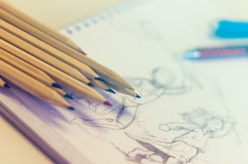 Colored pencils sitting on sketchbook, drawing, sketching