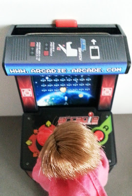 Aerial view of a modern dolls' house miniature arcade game, showing a slot for a mobile phone to be inserted into it.