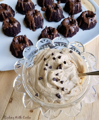 Perfect single sized chocolate cakes drizzled with a chocolaty glaze and topped with peanut butter whipped cream. They are a little indulgent and perfect for a party! big glass bowl of peanut butter whipped cream with mini chocolate chips with platter of mini bundts in the background
