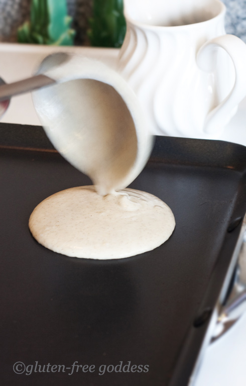 Pouring gluten-free pancake batter onto the griddle.