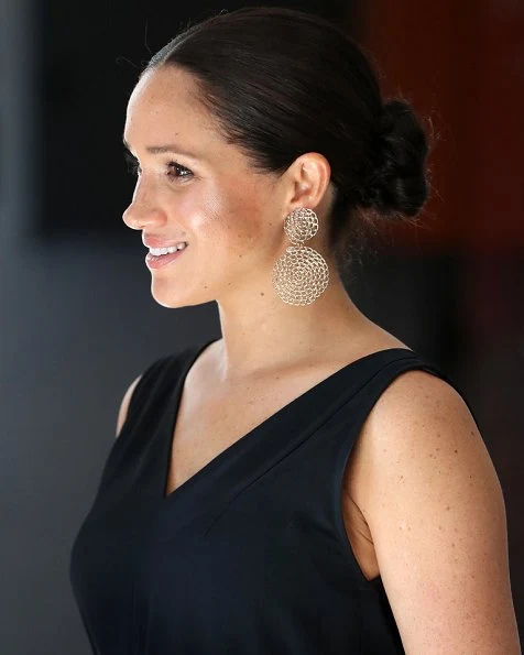 Meghan Markle wore Clup Monaco dremah silk midi dress and Everlane essential goweave jumpsuit. Gas earrings