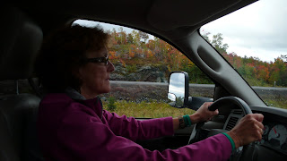 Liz driving the truck with fall landscape outside.