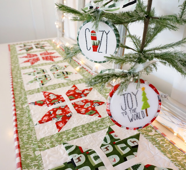 The joyful snowflake table runner is shown with coordinating embroidered ornaments