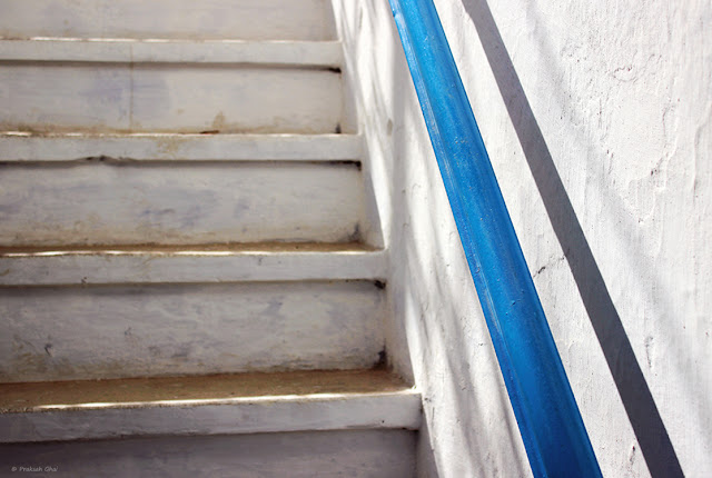 A Minimalist Photo of White Staircase with Blue side rail.