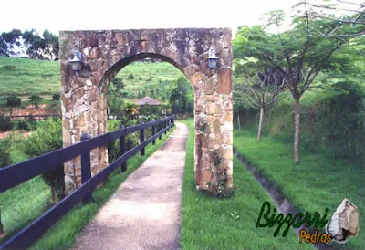 Pórtico de pedra, construído com pedra moledo, na execução da pista de cooper com o piso de cimentado, junto ao piquete dos cavalos, com a execução do paisagismo em sítio em Mairiporã-SP.