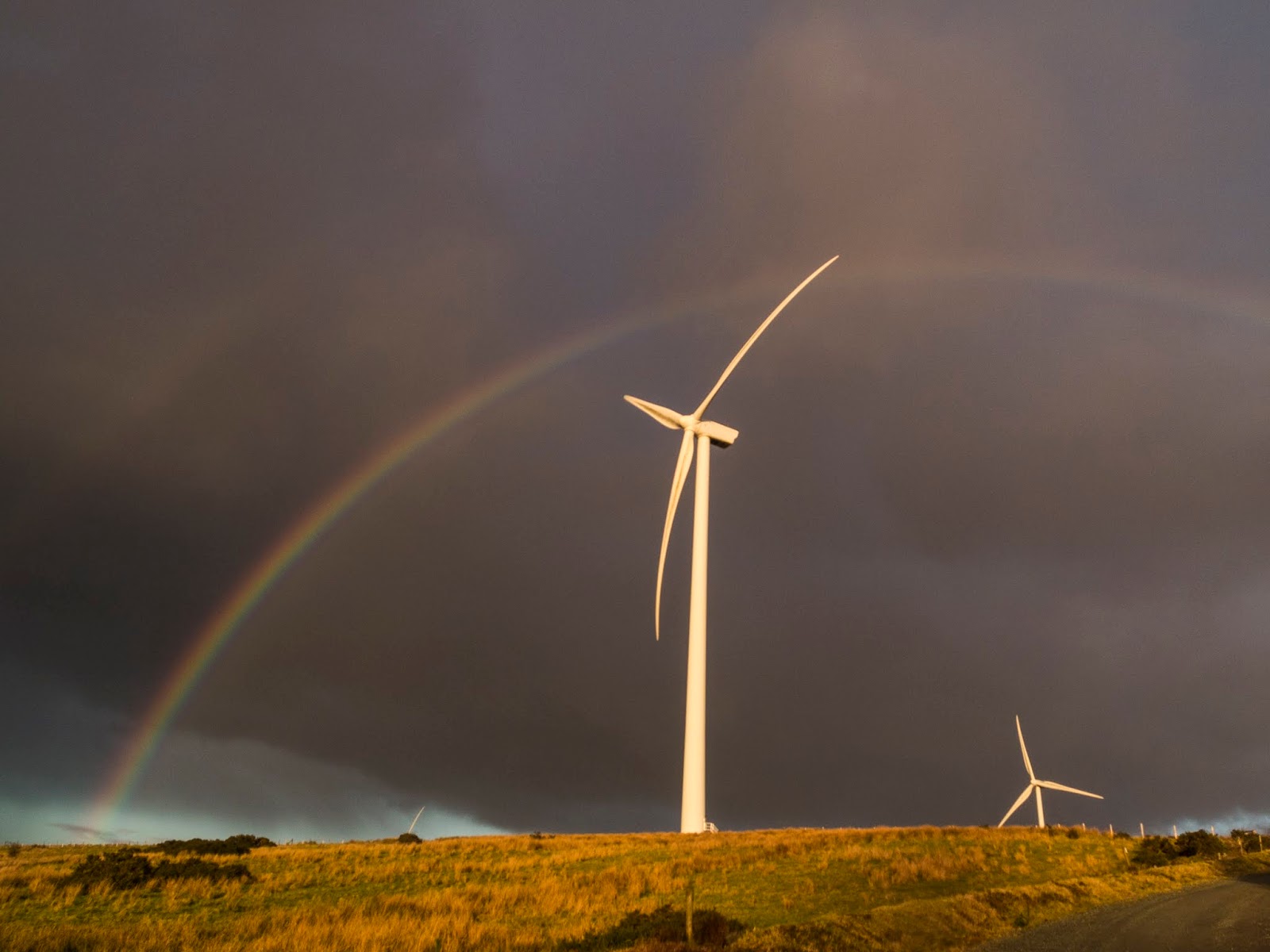Double Rainbow A double rainbow over a windmill in the sunlight with dark clouds above.