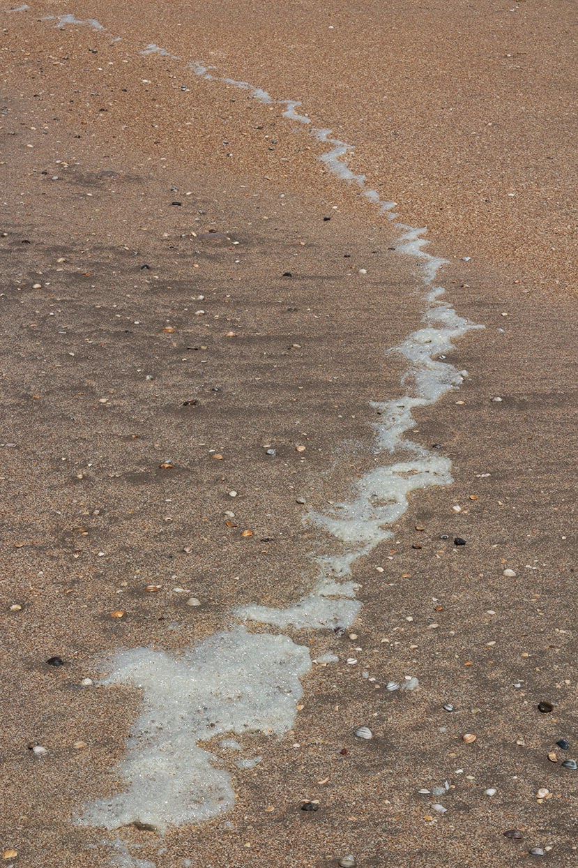 half a circle of sea foam on beach