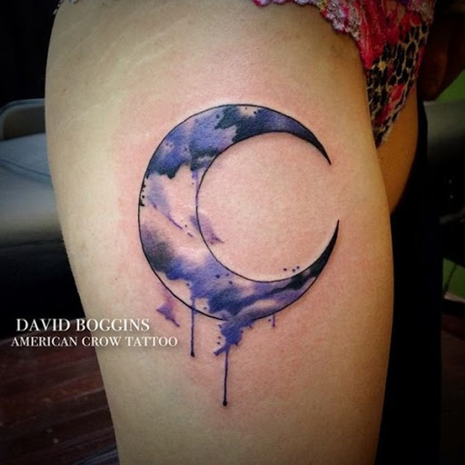 Uma lua crescente é manchadas de roxo e preto aquarelas neste tatuagem prestados em que o portador da coxa.