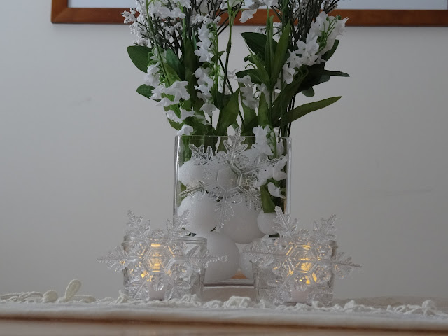 White lace scarf, white flowers, candles and clear snowflakes
