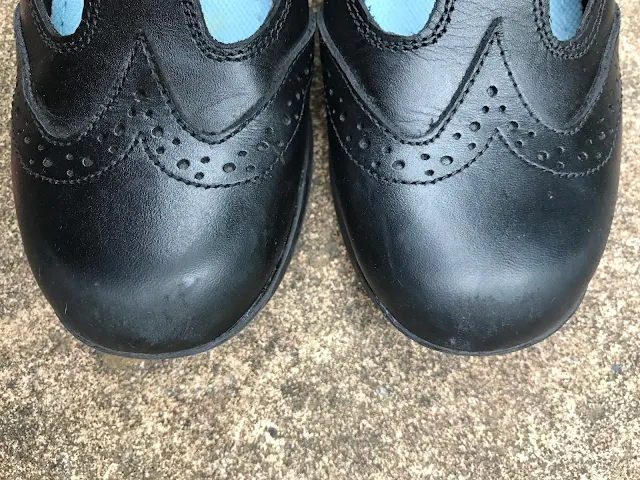 A close up of black school shoes with a small amount of scuffing