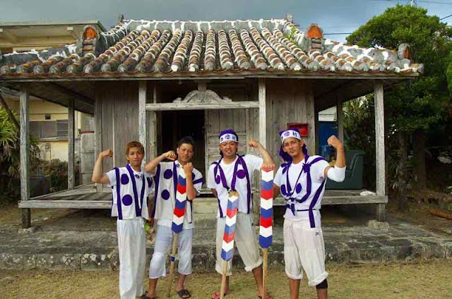 young men in traditional clothing pose at house of a priestess