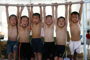 Pain. Chinese children hang up to a bar for 5 minutes during a gymn lesson