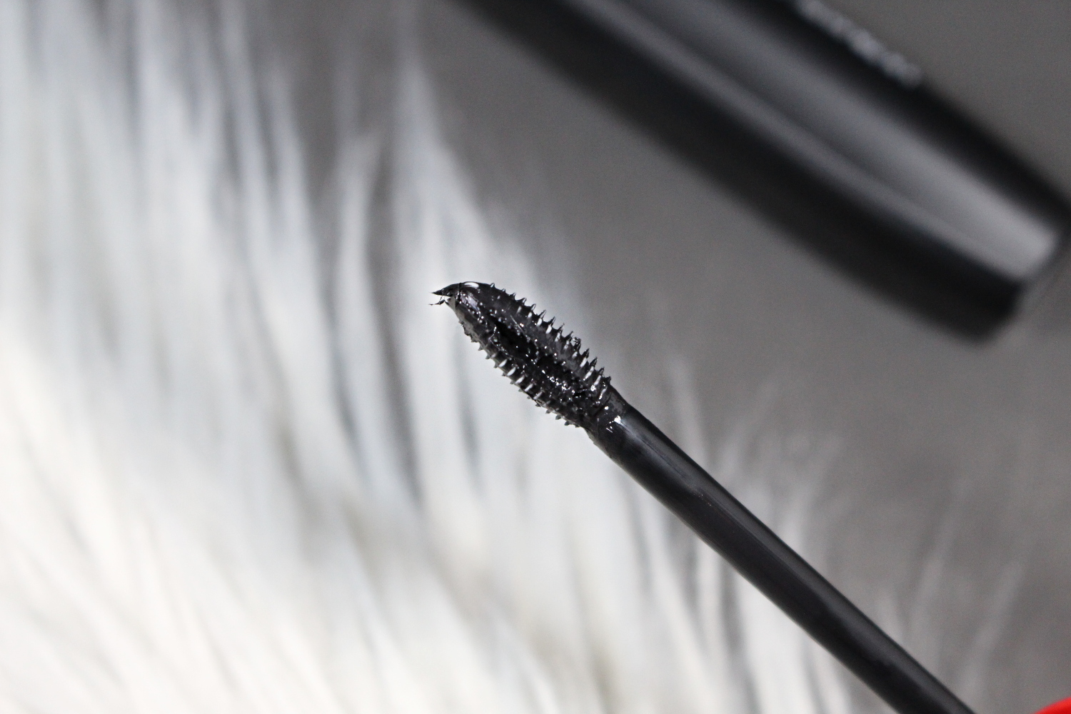 a close-up of Revlon Ultimate All-in-One Mascara on a gray faux fur rug