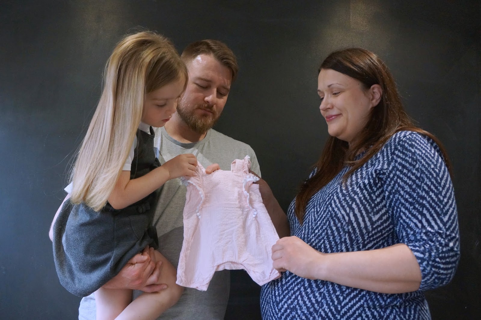 family looking at baby outfit