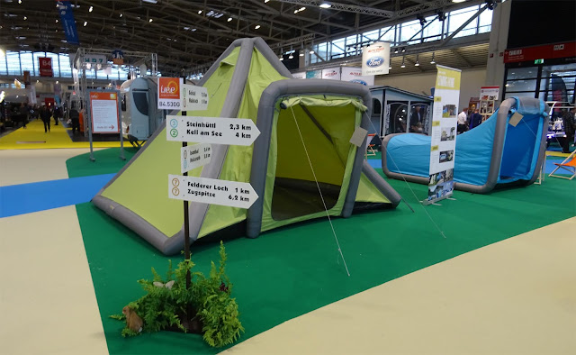 Camping Zelte in grün und blau mit Wegweisern auf der f.re.e Reisemesse
