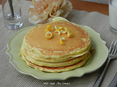 pancakes stacked on a plate with lemon zest on top on a green plate 