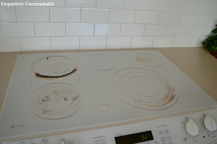 A very dirty white glass cooktop stove