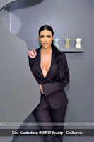 kim kardashian pop-up shop, खड़ी हुई किम अपने बड़े बड़े बूब्स के साथ काले कोट में