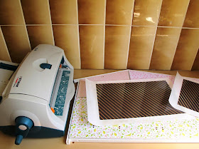 Two uncut pieces of scrapbooking paper, run though a Xyron sticker machine and sitting on the back wall of a Lundby Smaland 2015 dolls' house.