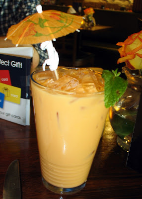 A Glass of Thai iced tea with cute umbrella and mint leaf