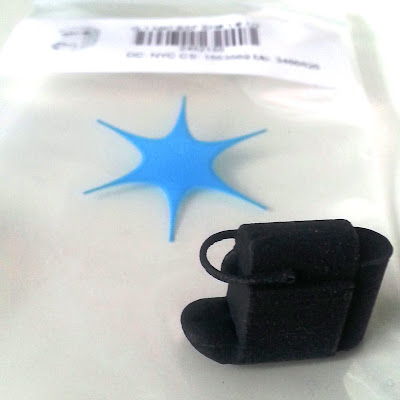 3D-printed miniature Nespresso machine displayed on the Shapeways bag it came in.